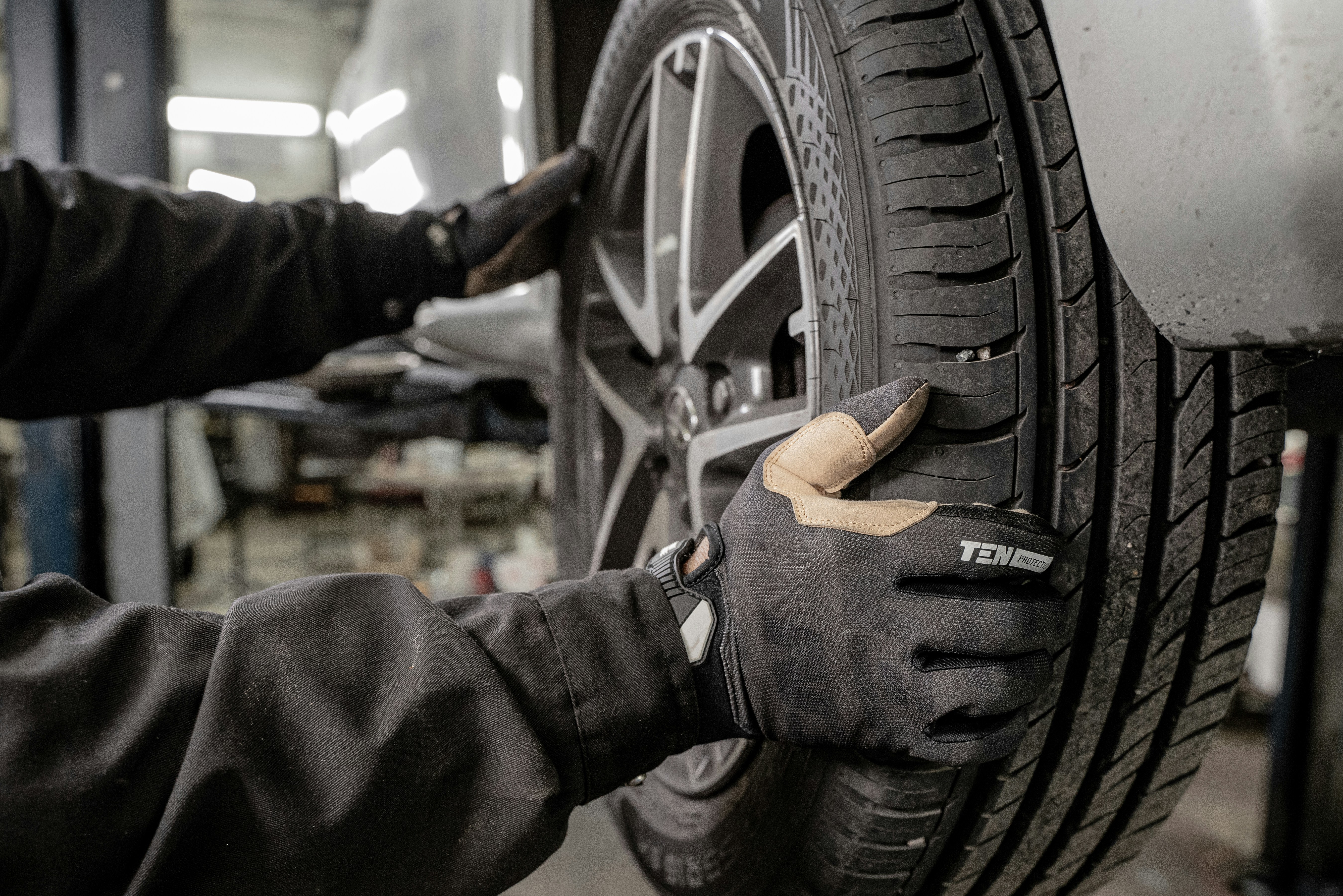 Mechanic in gloves inspecting tire tread in a service shop