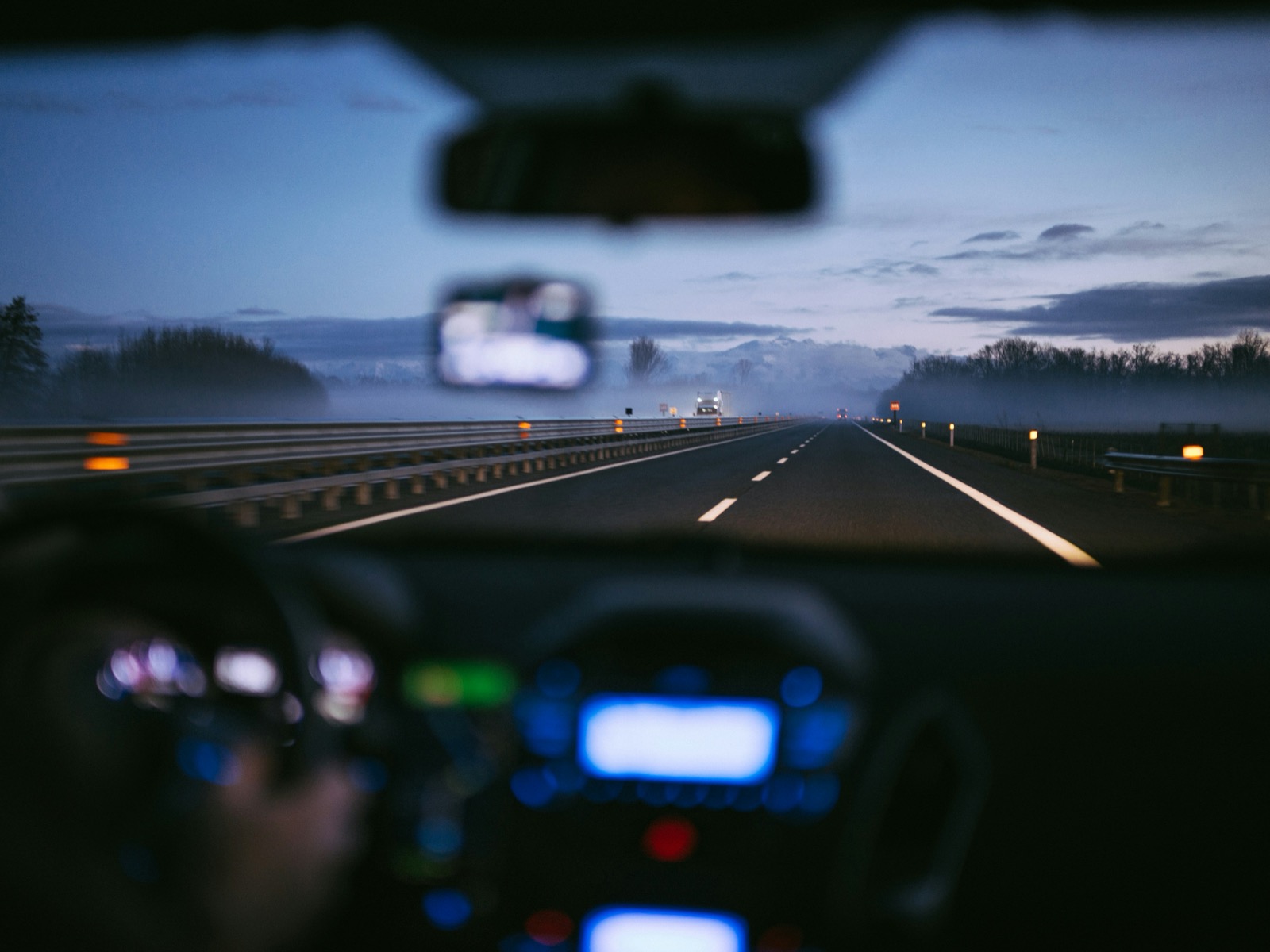 Dashboard view of a foggy highway at dusk