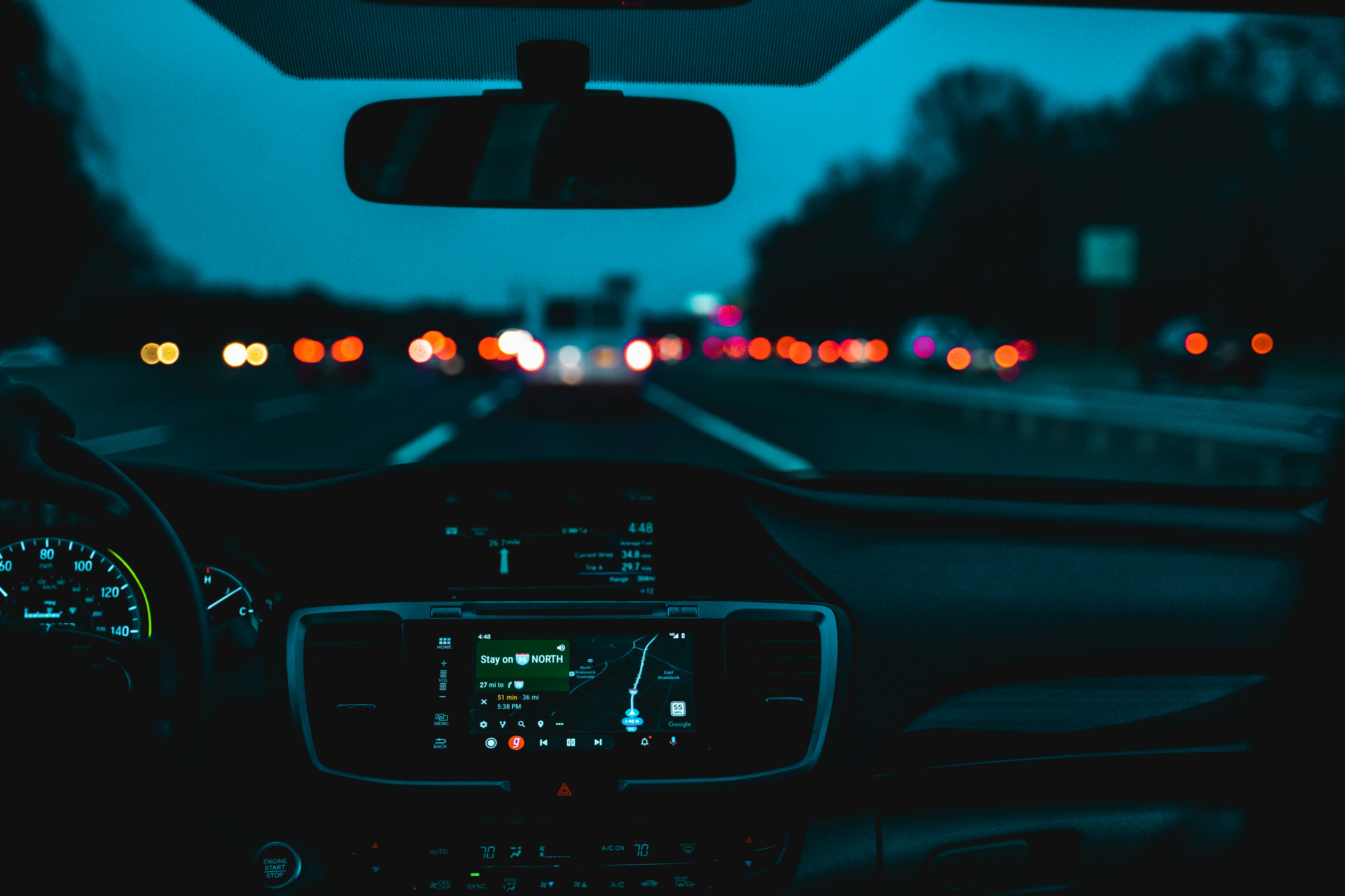 Dashboard view of a highway at night with cool blue tones and GPS navigation