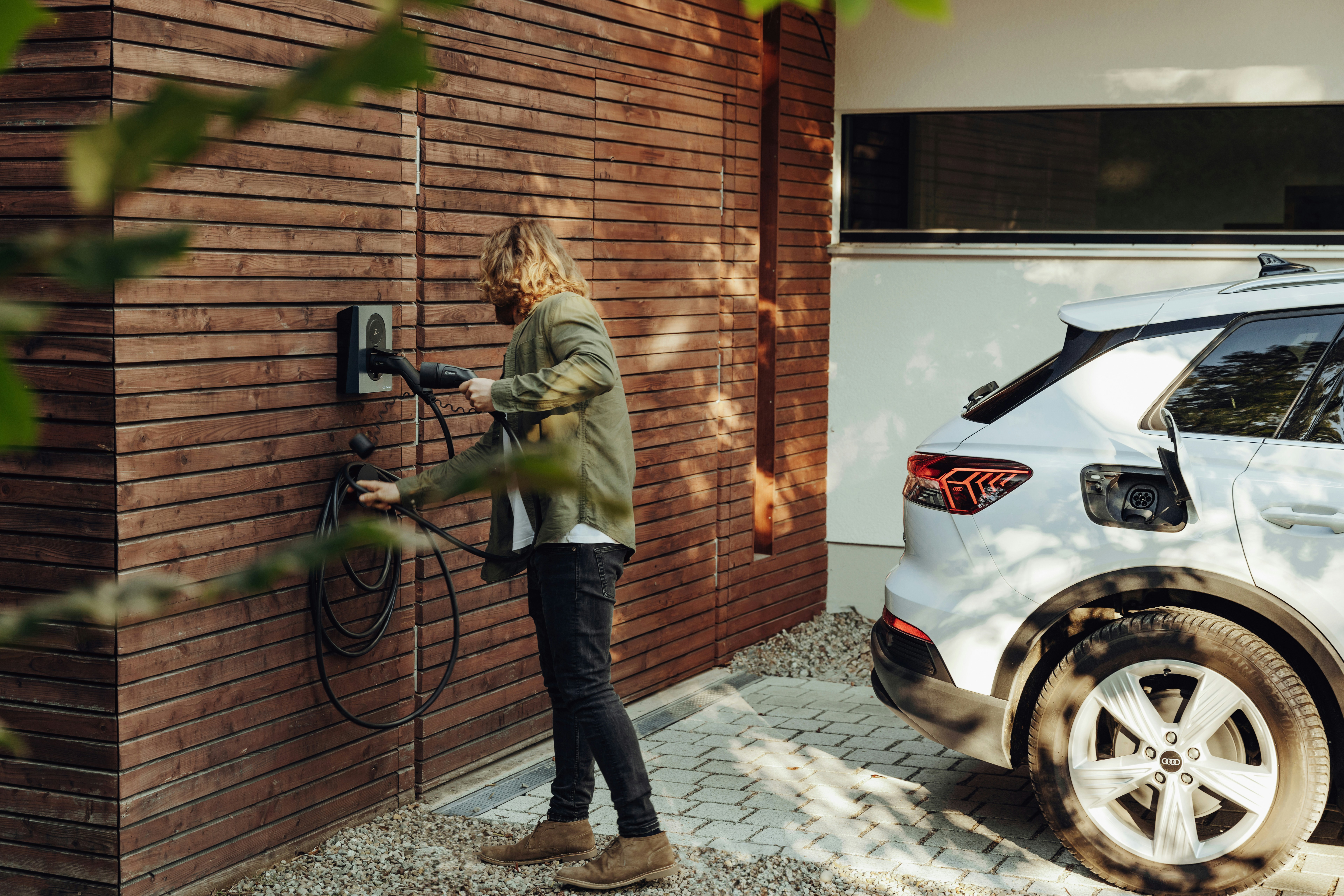 Person charging an electric vehicle at a home wall box