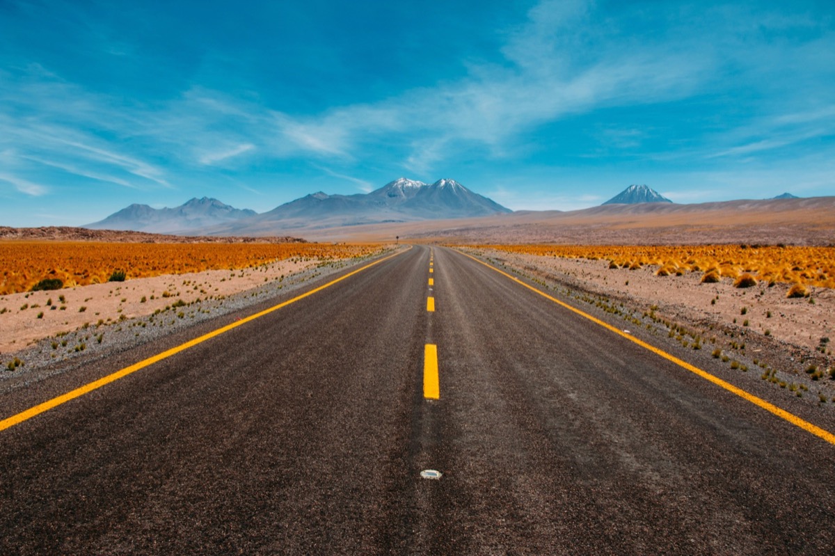 Open desert highway stretching toward distant mountains under blue sky