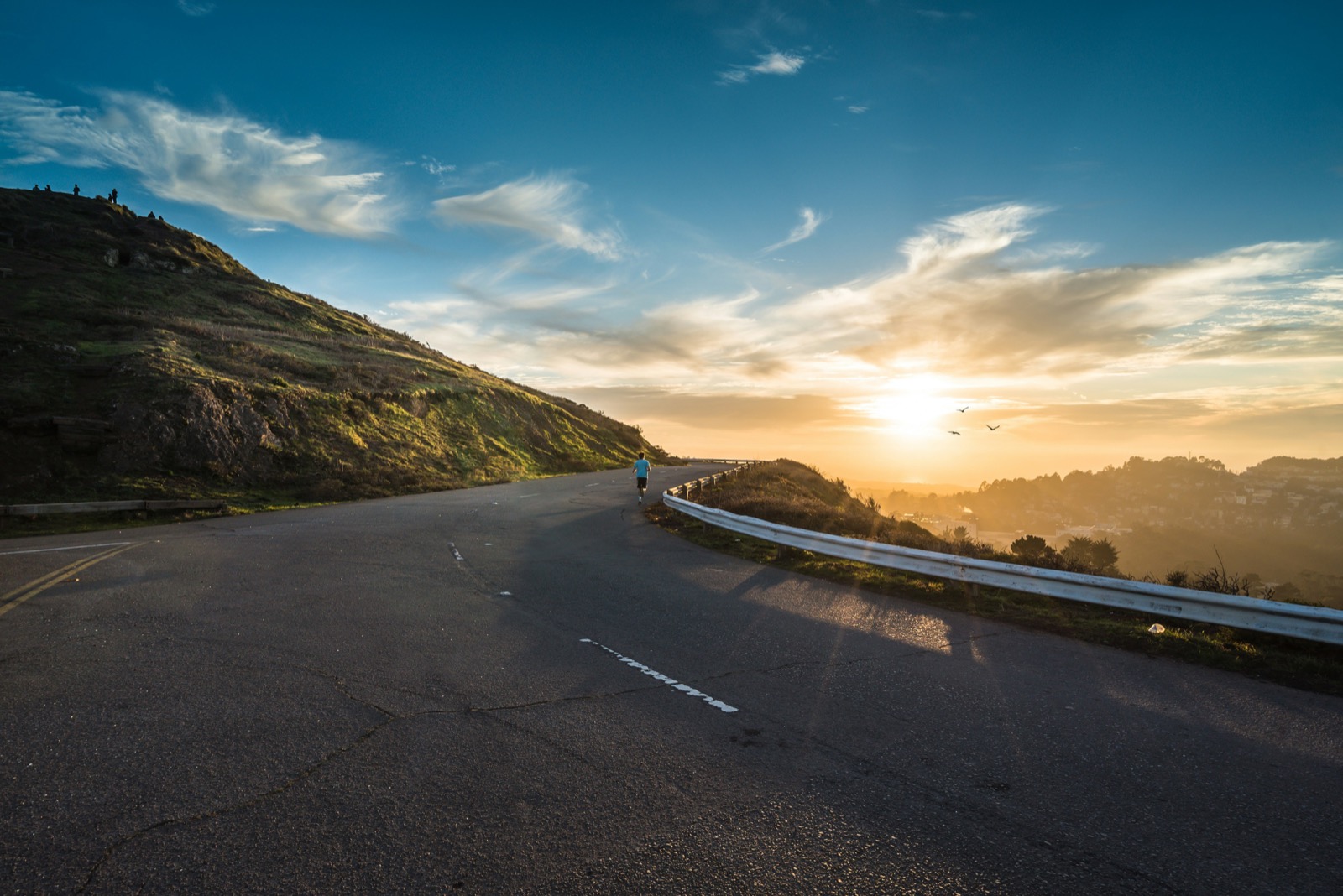 Winding hilltop road at sunset overlooking a coastal valley