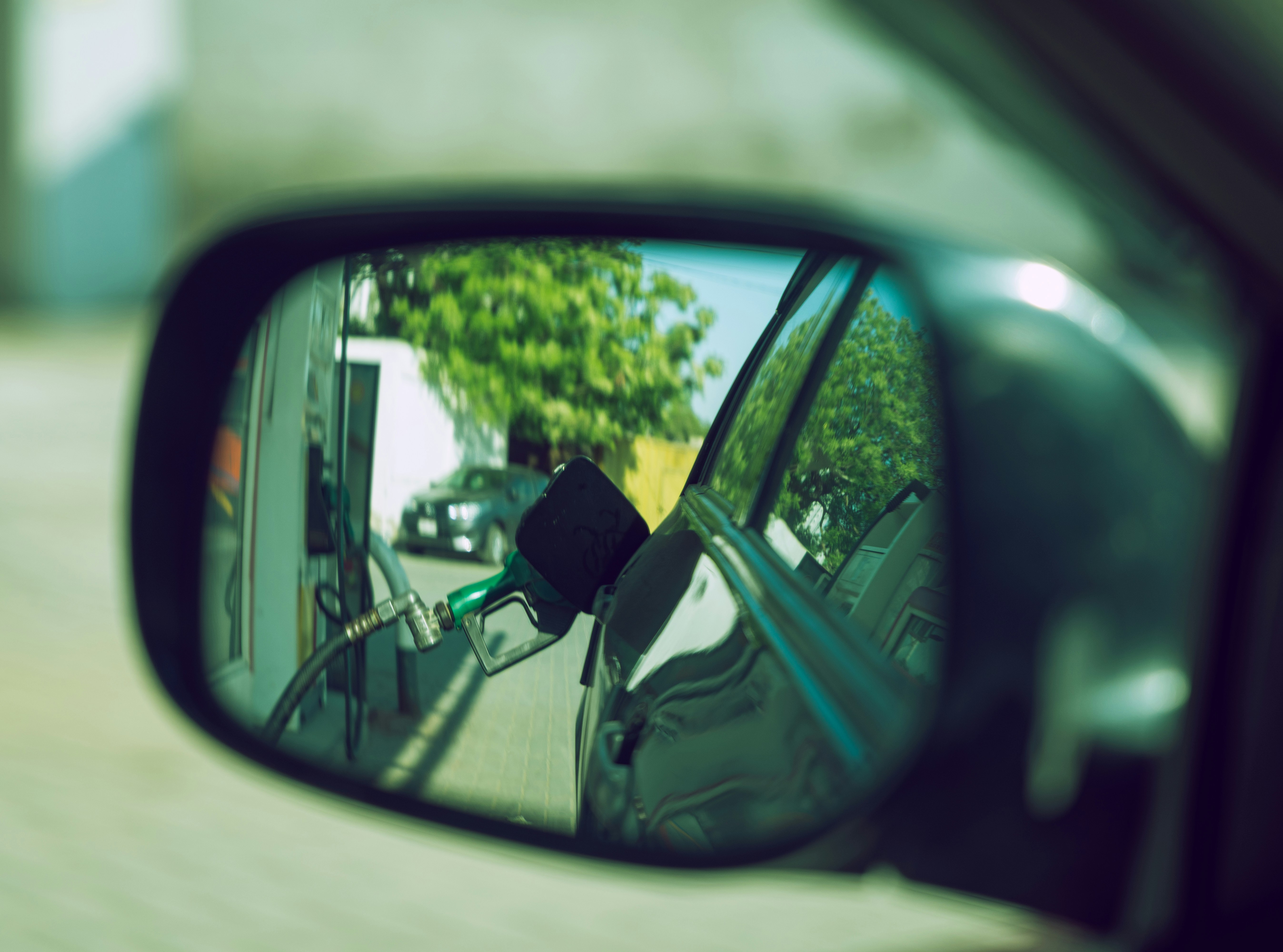Gas pump reflected in a car side mirror at a fuel station