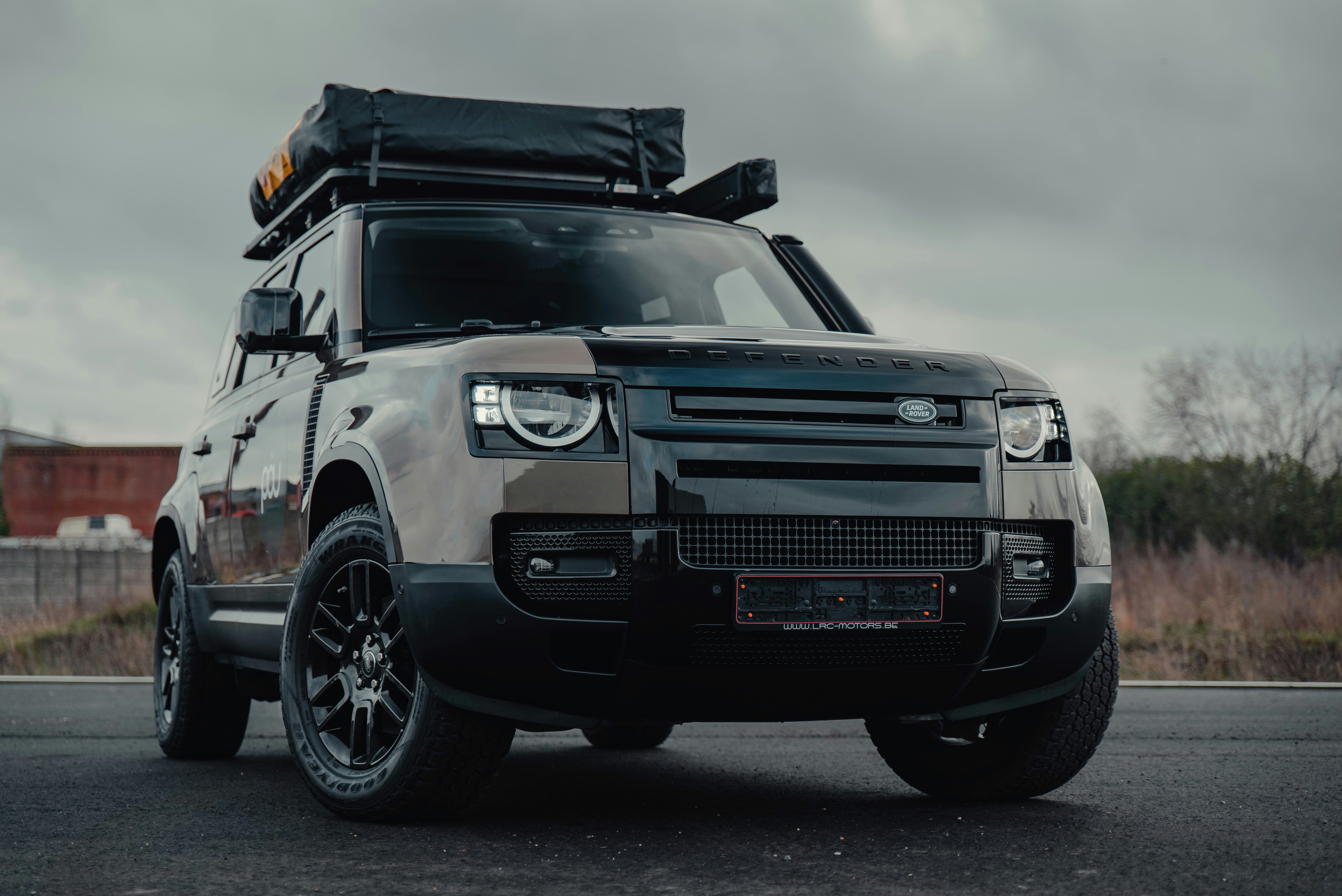 Land Rover Defender with rooftop tent parked in overcast light