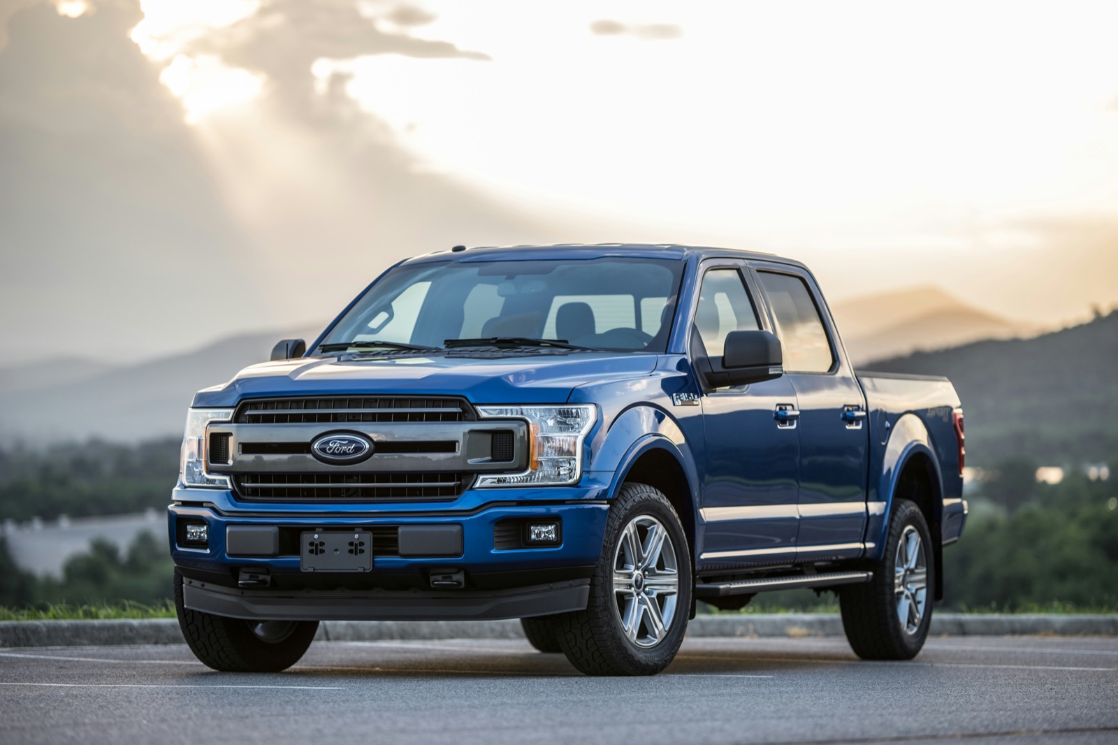 Blue Ford F-150 parked on a mountain overlook at golden hour