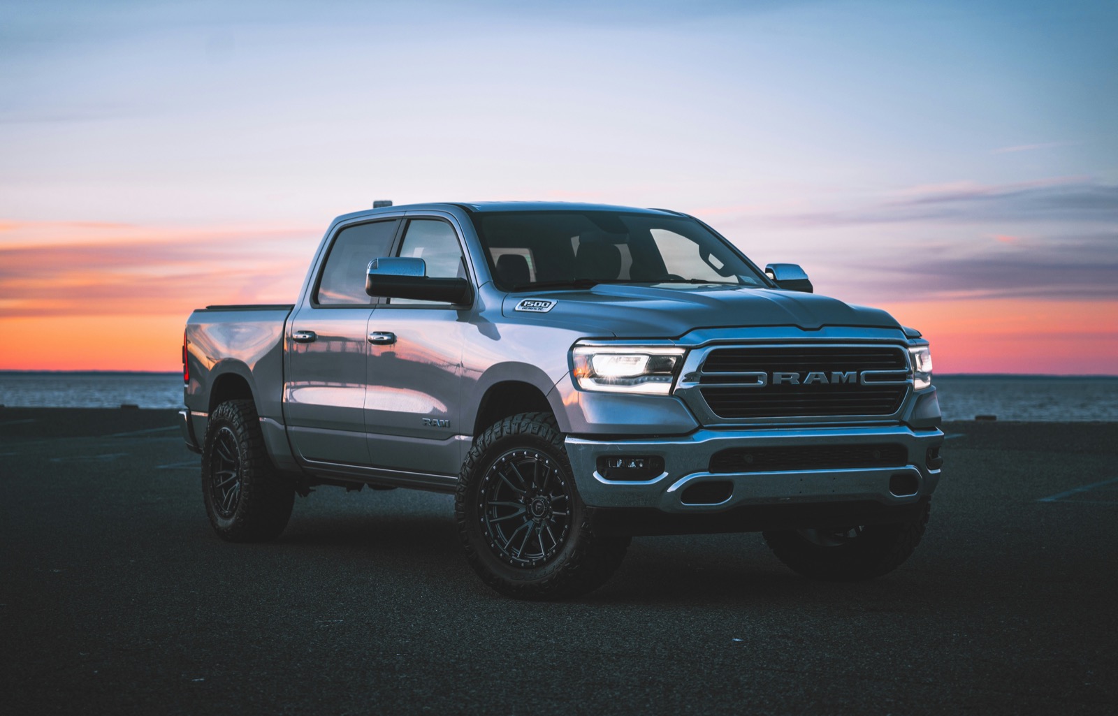 Ram 1500 pickup truck parked against a vivid ocean sunset